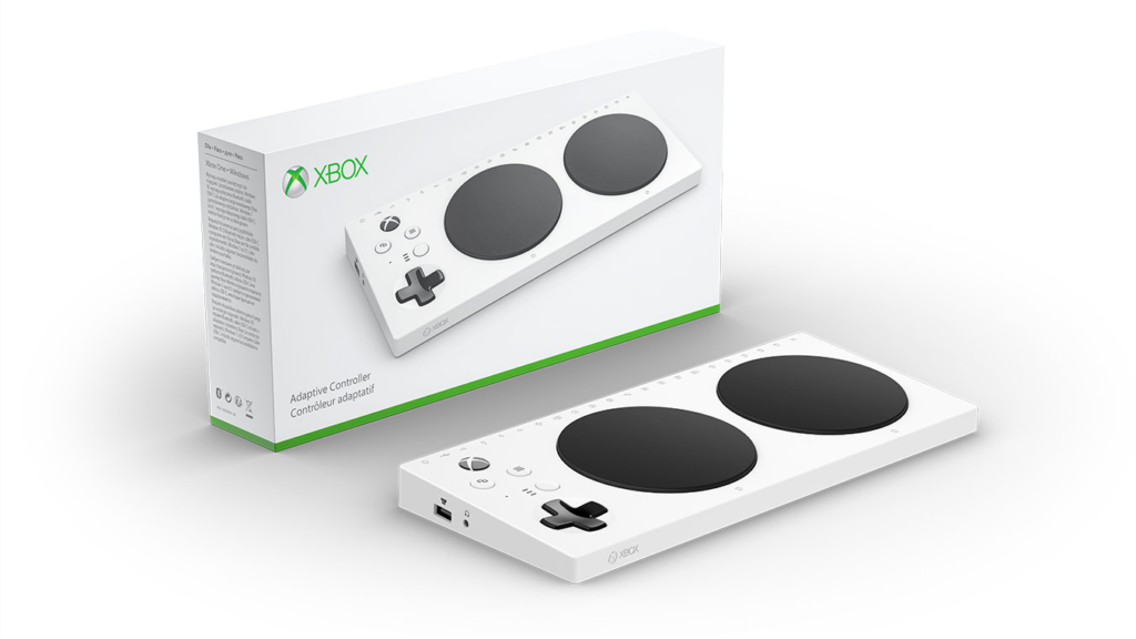 The Xbox Adaptive Controller. White rectangular controller designed to help enable people with disabilities play video games. The controller includes a plus-shaped directional pad and two large black circles on the top.