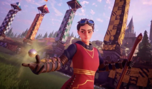 A Seeker in Harry Potter: Quidditch Champions is floating on her broom on Quidditch pitch. She is wearing a red uniform and the Golden Snitch is hovering just above her hand. 